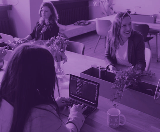 Three women in an office. One of the women is smiling.