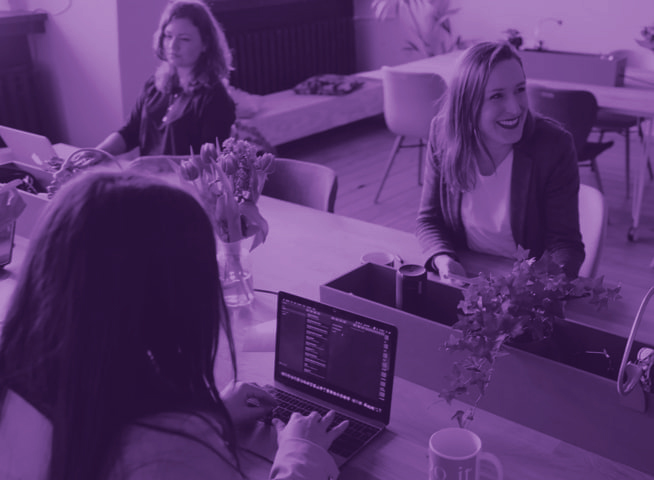 Three women in an office. One of the women is smiling.